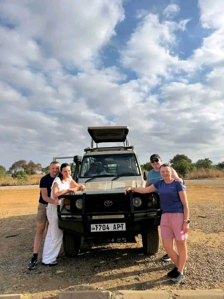 Travelers gathered beside a safari Land Cruiser in Tanzania