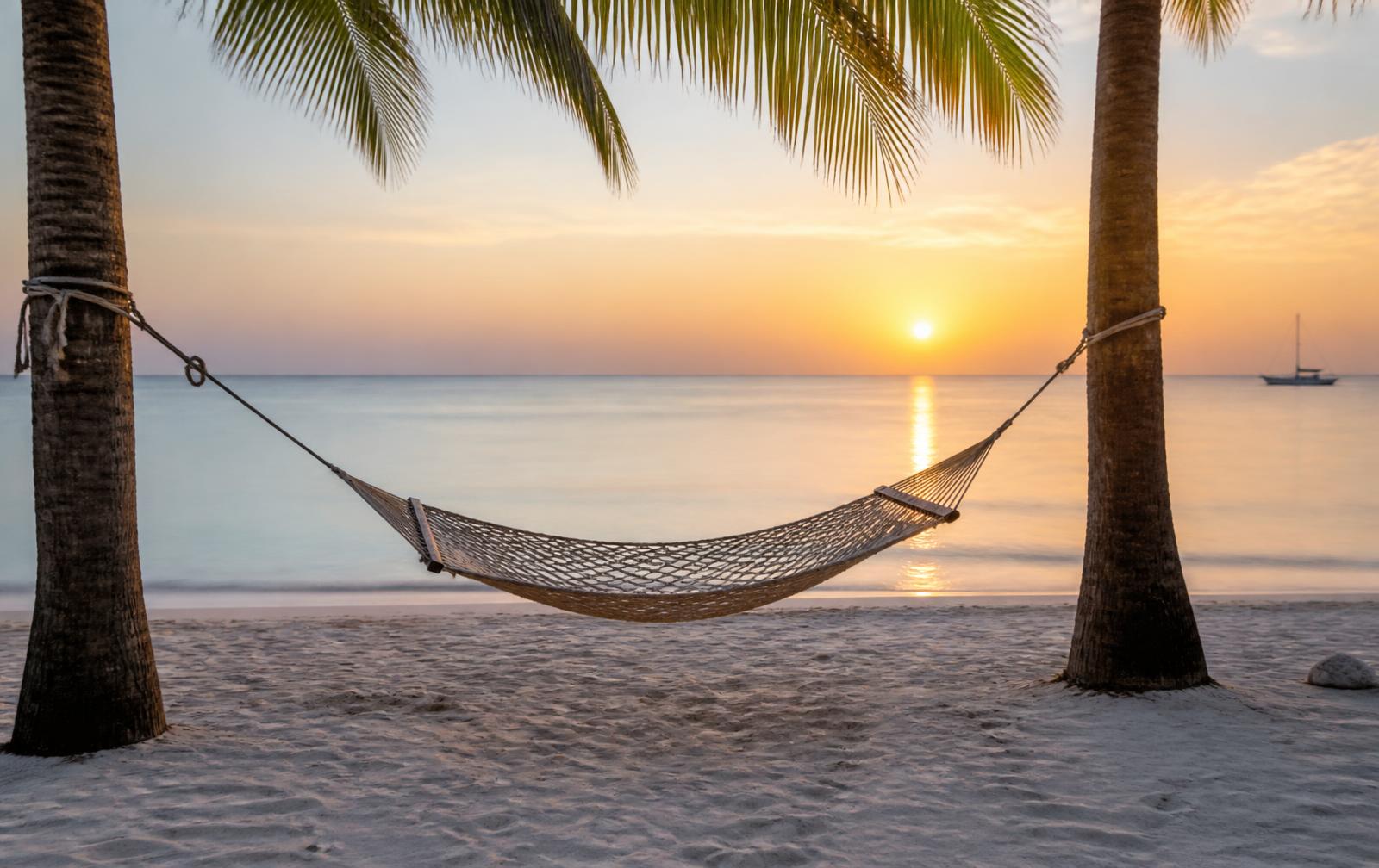 Empty hammock between palms on a quiet Zanzibar beach at sunrise