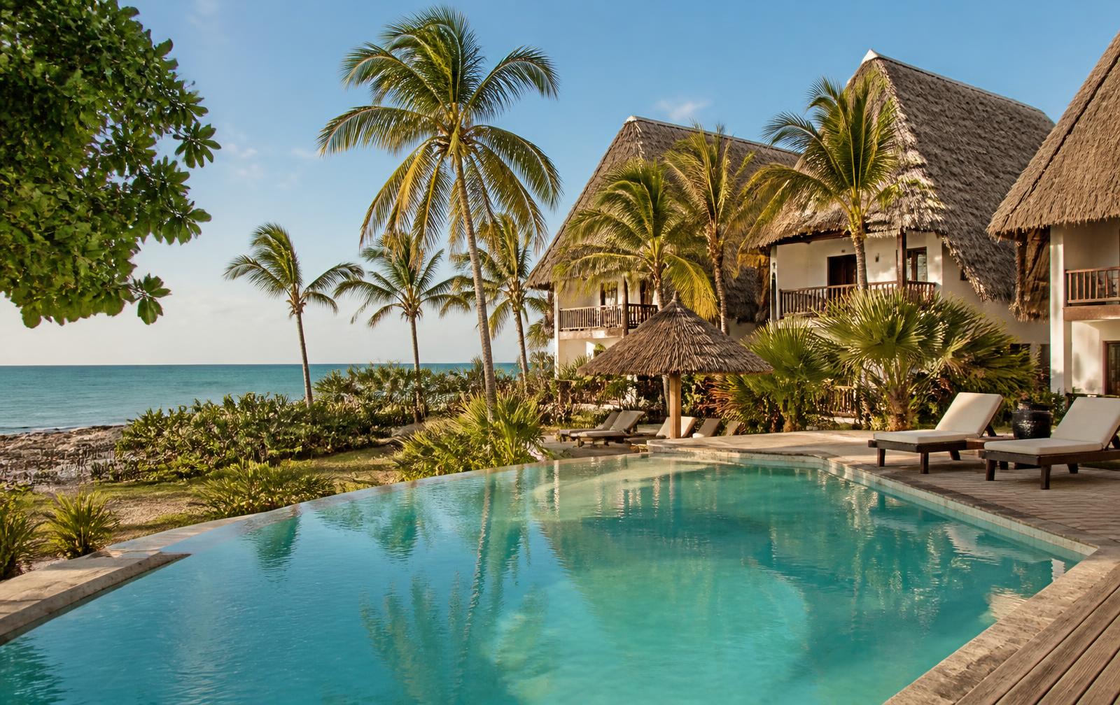Thatched beach hotel bungalows and pool beside the ocean in Zanzibar