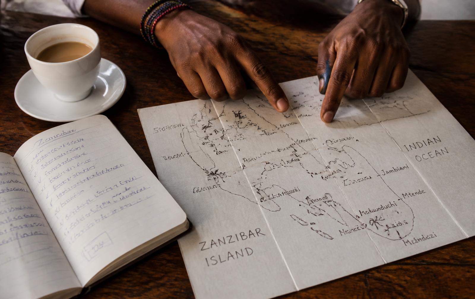 Hands pointing at a hand-drawn Zanzibar island map while planning a trip