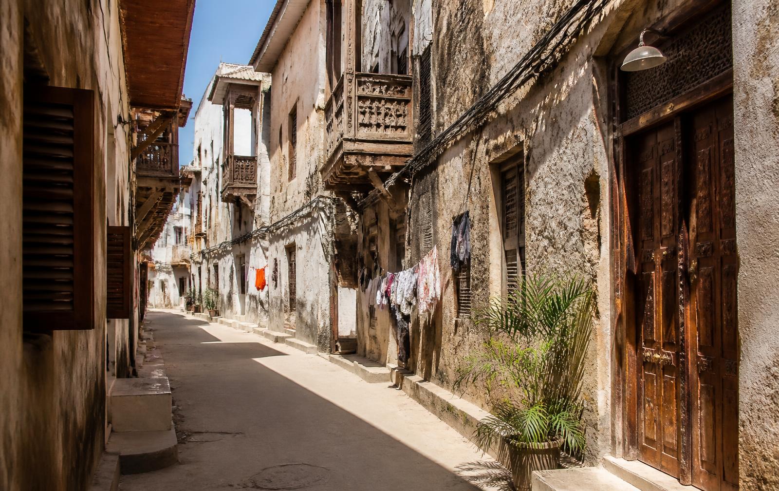 Narrow sunlit alley with carved balconies in Stone Town, Zanzibar