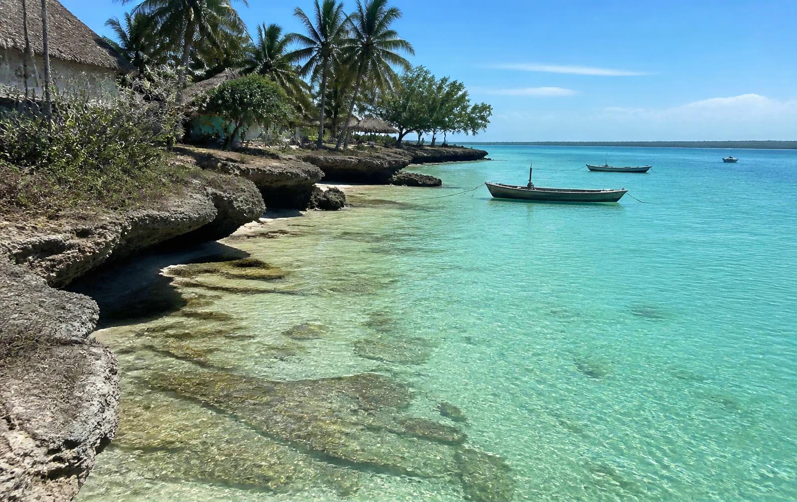 Sheltered turquoise cove with coral rocks and fishing boats at Pongwe, Zanzibar