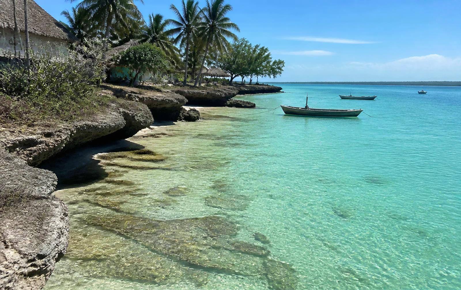 Sheltered turquoise cove with coral rocks and fishing boats at Pongwe, Zanzibar